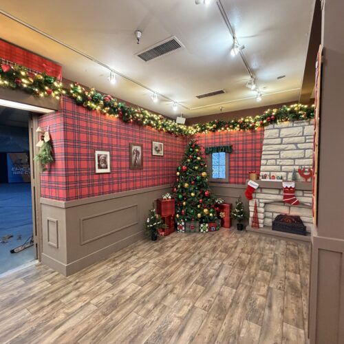 Plaid scenic walls with framed artwork and holiday garlands at Six Flags Magic Mountain.