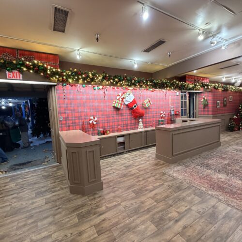 Holiday front-desk area inside Santa’s Workshop with garlands and oversized stockings.